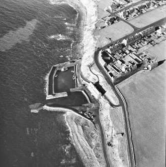 Oblique aerial view centred on the harbour, with the warehouse, pillbox and icehouse adjacent, taken from the W.