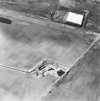 Oblique aerial view of the reservoir and the remains of the buildings, farmstead and chambered cairn, taken from the NE.