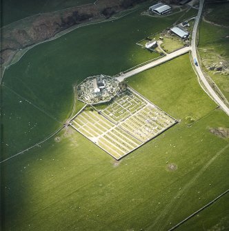 Oblique aerial view centred on the church and burial-ground with the farmstead adjacent, taken from the E.