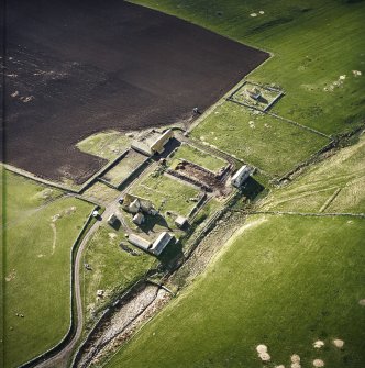 Oblique aerial view centred on the farmstead and mausoleum, taken from the NW.