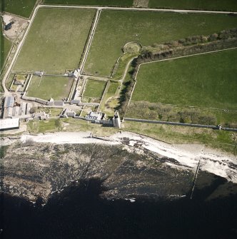 Oblique aerial view centred on the remains of the castle with the farmsteading adjacent, taken from the NW.