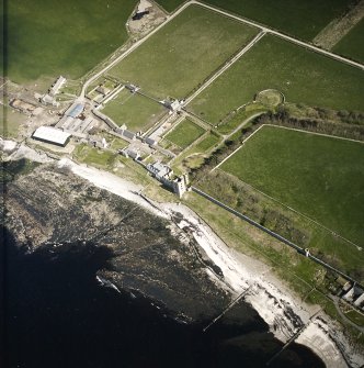 Oblique aerial view centred on the remains of the castle with the farmsteading adjacent, taken from the WNW.