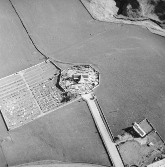 Oblique aerial view centred on the church and burial-ground with the farmstead adjacent, taken from the N.