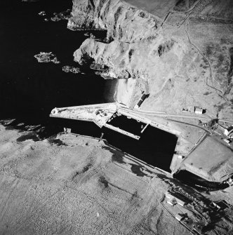 Oblique aerial view centred on the harbour and lighthouse with the warehouses adjacent, taken from the NE.