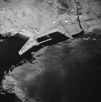 Oblique aerial view centred on the harbour and lighthouse with the warehouses and road bridge adjacent, taken from the E.