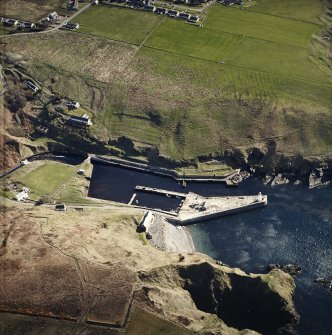 Oblique aerial view centred on the harbour and lighthouse with the warehouses adjacent, taken from the SW.