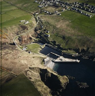 Oblique aerial view centred on Lybster harbour and lighthouse with the warehouses and road bridge adjacent, taken from the SW.