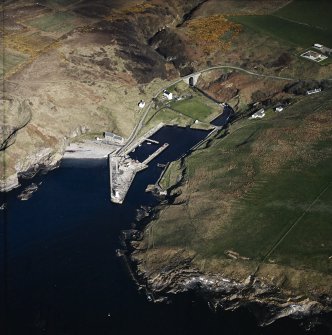 Oblique aerial view centred on the harbour and lighthouse with the warehouses and road bridge adjacent, taken from the ESE.