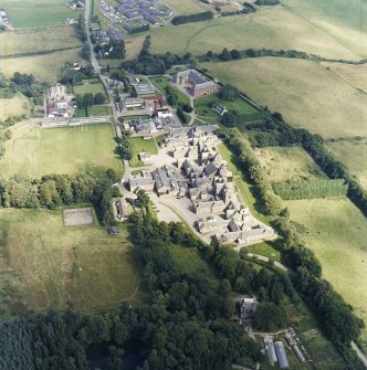 Oblique aerial view centred on the hospital and churches, with the farmsteading adjacent, taken from the SW.