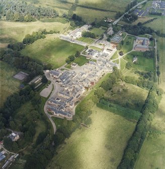 Oblique aerial view centred on the hospital and churches, with the farmsteading adjacent, taken from the S.