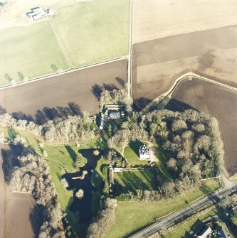 Oblique aerial view centred on the country house, farmhouse and stables taken from the SW.