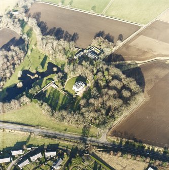 Oblique aerial view centred on the country house, farmhouse and stables taken from the S.