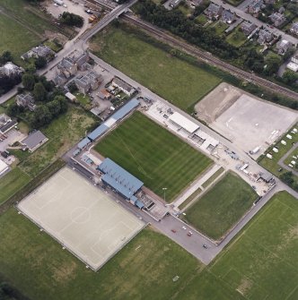 Oblique aerial view centred on the football stadium with courthouse and police station adjacent, taken from the ENE.