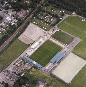 Oblique aerial view centred on the football stadium with courthouse and police station adjacent, taken from the SSE.