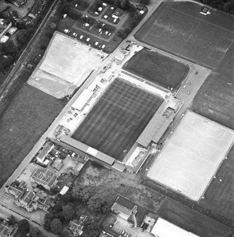 Oblique aerial view centred on the football stadium with courthouse and police station adjacent, taken from the SSE.