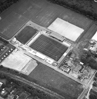 Oblique aerial view centred on the football stadium with courthouse and police station adjacent, taken from the WSW.