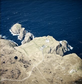 Oblique aerial view centred on the lighthouse, keepers' cottages, cottages and support buildings with the radar station adjacent, taken from the SSE.
