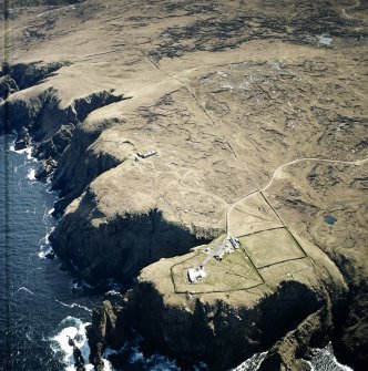 Oblique aerial view centred on the lighthouse, keepers' cottages, cottages and support buildings with the radar station adjacent, taken from the NNW.