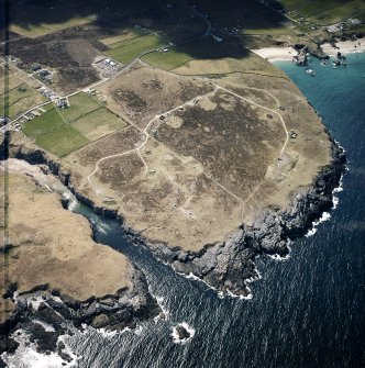 Oblique aerial view centred on the remains of the radar station with caves and crofting township adjacent, taken from the ENE.