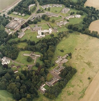 Oblique aerial view centred on the hospital before development and house, taken from the SW.