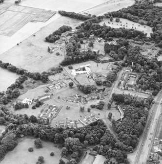 Oblique aerial view centred on the hospital before development and house, taken from the NE.