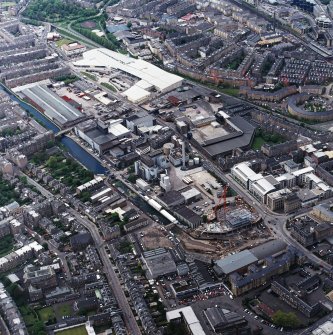 Oblique aerial view centred on the brewery with the leisure centre and cinema, canal, canal basin and canal bridge adjacent, taken from the ESE.