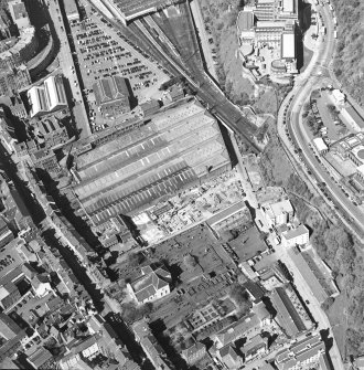 Oblique aerial view centred on the garage with the church and graveyard, New Street, Tolbooth Wynd and the Canongate adjacent, taken from the E.