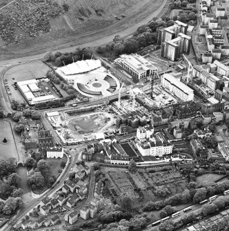 Oblique aerial view centred on the Scottish parliament under construction with `Our Dynamic Earth¿ and burial ground adjacent, taken from the NNW.