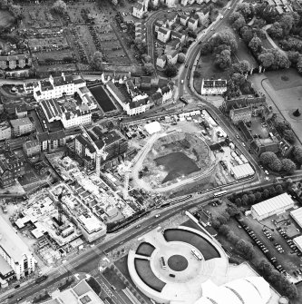 Oblique aerial view centred on the Scottish parliament under construction with `Our Dynamic Earth' and burial ground adjacent, taken from the S.