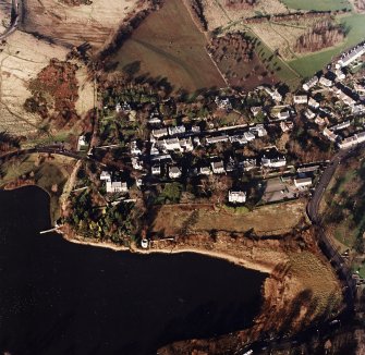 Oblique aerial view of Edinburgh centred on Duddingston Village with the parish church and south lodge visible, taken from the S.