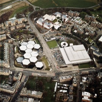 Oblique aerial view centred on the offices with the swimming pool, school, burial ground and halls of residence adjacent, taken from the SW.