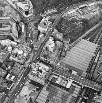 Oblique aerial view centred on the redevelopment of the former post office, with the register house under repair and the railway station and hotel adjacent, taken from the SW.