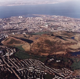 Oblique aerial view of Edinburgh centred on Holyrood Park, taken from the SSW.