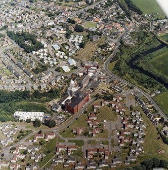 Oblique aerial view of former distillery, taken from SSW, with Saladin-box maltings in the foreground left.