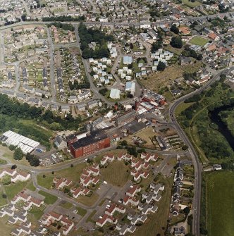 Oblique aerial view of former distillery, taken from SSE, with Saladin-box maltings the foreground left.