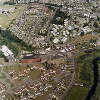 Oblique aerial view of former distillery, taken from SSE, with Saladin-box maltings in the foreground left and malt-extract buildings to the right.