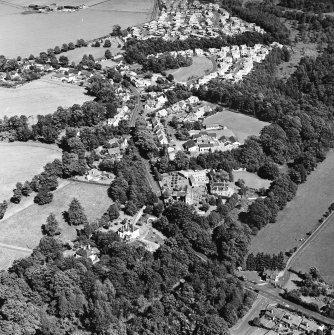 Oblique aerial view centred on the church, burial ground and village, taken from the WSW.