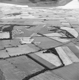 Oblique aerial view of East Fortune Airfield centred on the airfield with the cropmarks of a possible enclosure adjacent, taken from the E.