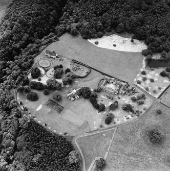 Oblique aerial view of Dunglass centred on a church and stables, taken from the NNE.