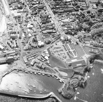 Oblique aerial view centred on fishermen's housing at Victoria Place, barracks and leisure centre with the harbour and castle adjacent, taken from the N.