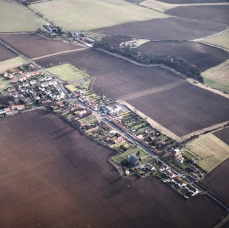 General oblique aerial view centred on the village with the building and farmsteading adjacent, taken from the NW.