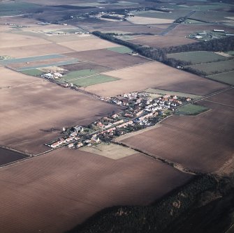 General oblique aerial view looking across the village towards the airfield and museum, taken from the SW.