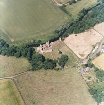 Oblique aerial view centred on the remains of the castle and garden with cottage and smithy adjacent, taken from the SSW.