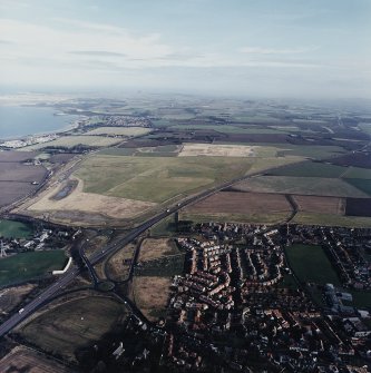 General oblique aerial view looking across the school, town and restored agricultural land towards Longniddry and North Berwick Law, taken from the SW.