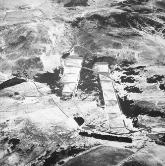 General oblique aerial view centred on the rifle range with the remains of the fort, trenches, ring-ditch house and rig adjacent, taken from the SSE.
