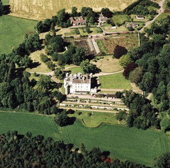 Oblique aerial view centred on the country house with walled and terraced gardens, stables and laundry adjacent, taken from the S.