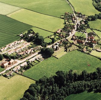 Oblique aerial view centred on the church, burial ground, old church, mausoleum and village, taken from the NE.