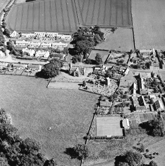 Oblique aerial view centred on the church, burial ground, old church, mausoleum and village, taken from the NW.
