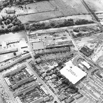 Oblique aerial view centred on the remains of the works with church and burial ground adjacent, taken from the NNE.