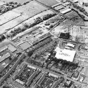 Oblique aerial view centred on the remains of the works with church and burial ground adjacent, taken from the NE.